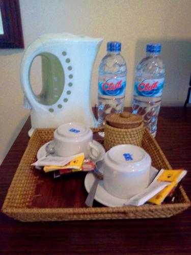 a tray with two bottles of cocacola water and a tea set at Manggar Indonesia Hotel in Kuta