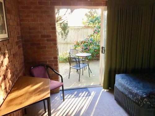 a room with a patio with chairs and a table at Inverloch Central Motor Inn in Inverloch
