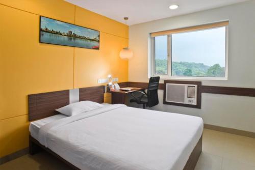 a bedroom with a bed and a desk and a window at Ginger Ahmedabad Vastrapur in Ahmedabad