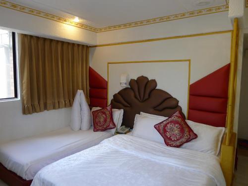 um quarto de hotel com duas camas com lençóis brancos e almofadas vermelhas em Aloha Hotel em Keelung