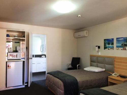 a hotel room with a bed and a refrigerator at Grosvenor Motel in Hamilton