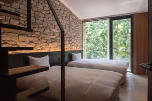 two beds in a room with a stone wall at Villa El Cielo Hakuba in Hakuba