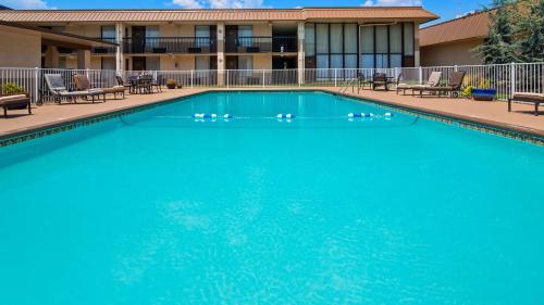 a large blue swimming pool with chairs and a building at Best Western Tulsa Airport in Tulsa