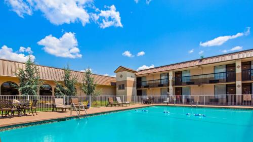 a pool in front of a hotel with patio furniture at Best Western Tulsa Airport in Tulsa