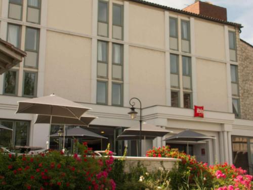 a building with an umbrella and flowers in front of it at ibis Périgueux Centre in Périgueux