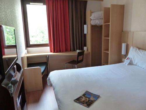 a hotel room with a bed and a desk and a window at ibis Périgueux Centre in Périgueux