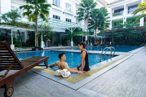 a woman and a boy sitting next to a swimming pool at Gallery Prawirotaman Hotel in Yogyakarta