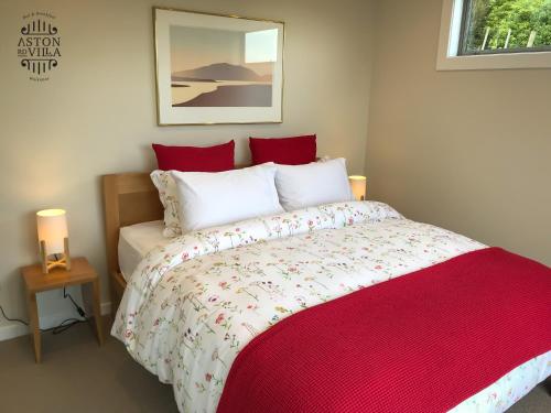 a bedroom with a bed with a red and white comforter at Aston Road Villa Bed & Breakfast in Waikanae