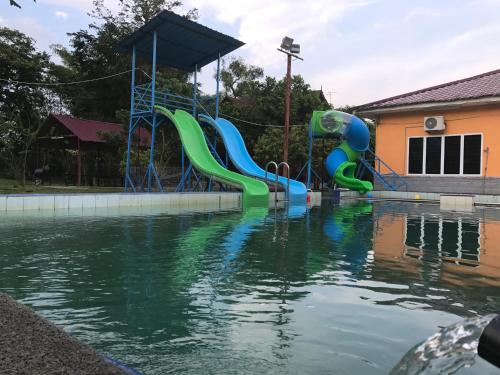 a pool of water with a playground with a water slide at Happy Paradise in Kampung Janda Baik