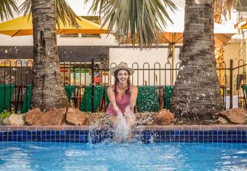 une femme assise à l'eau dans une piscine dans l'établissement YHA Alice Springs, à Alice Springs