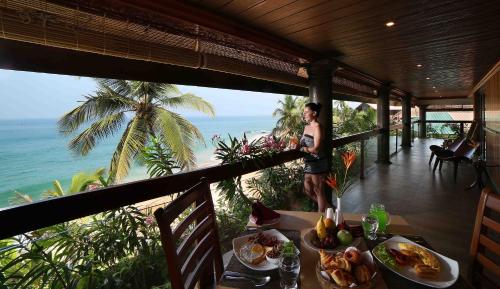 a woman standing on a balcony with a table with food at Uday Samudra Leisure Beach Hotel & Spa in Kovalam
