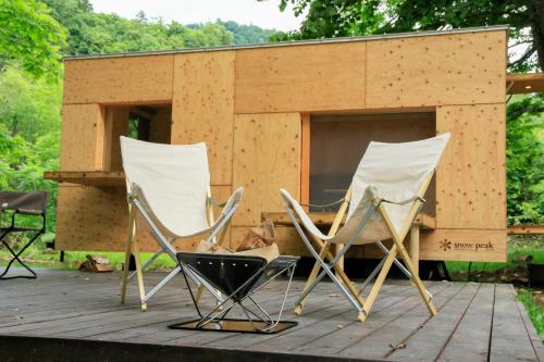 three chairs sitting on a deck with a shed at Snow Peak Jyubako（AKAIGAWA TOMO PLAYPARK） in Akaigawa