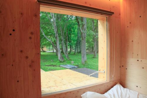 a window in a wooden room with a view of a yard at Snow Peak Jyubako（AKAIGAWA TOMO PLAYPARK） in Akaigawa