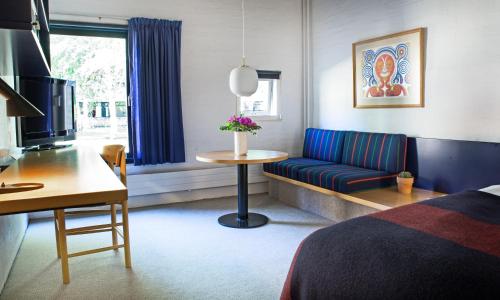 グレーノにあるKysthotelletのベッド、ソファ、テーブルが備わるホテルルームです。
