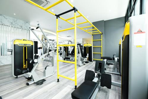 a gym with yellow equipment and tread machines at P Plus Hotel in Pattaya Central