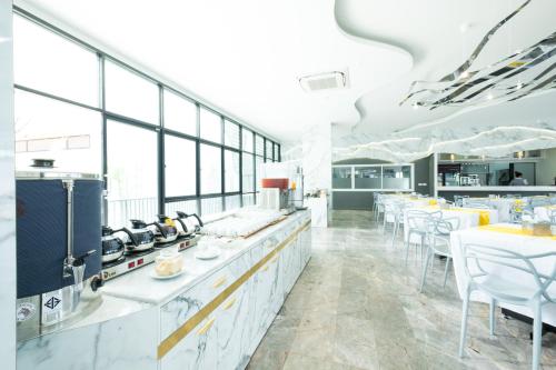 a restaurant with white tables and white chairs at P Plus Hotel in Pattaya Central