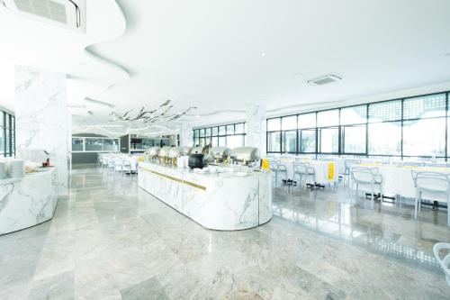 a large room with white tables and white chairs at P Plus Hotel in Pattaya Central