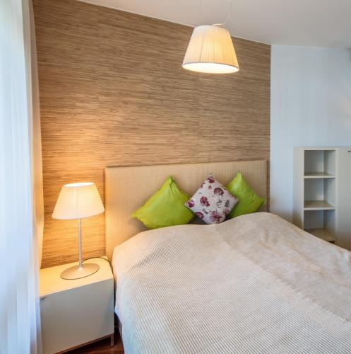 a bedroom with a bed with green pillows and a lamp at Luxury City Center Apartments in Helsinki