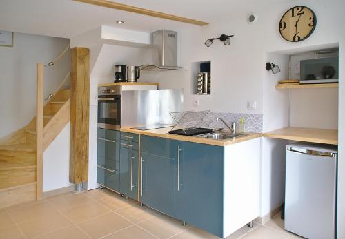 una cocina con armarios azules y un reloj en la pared en L'Estampe, en Montagne