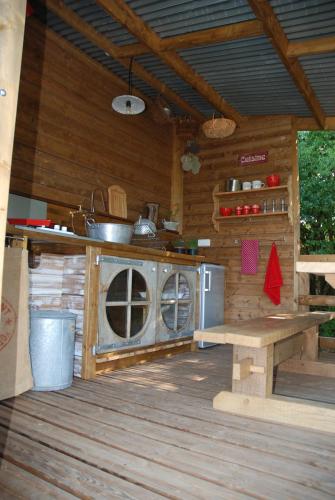 - une cuisine dans une cabane en rondins avec cuisinière dans l'établissement La Cabane Du Verger, à Salives