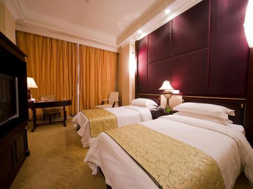 a hotel room with three beds and a television at Ramada Plaza Sino-Bay Shanghai in Fengxian