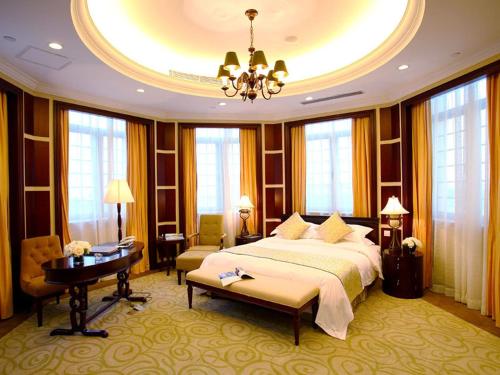 a hotel room with a bed and a table and windows at Ramada Plaza Sino-Bay Shanghai in Fengxian