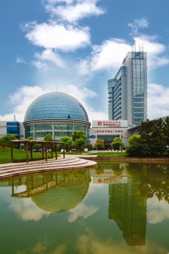 a view of a building with a pond in front of it at Ramada Plaza Sino-Bay Shanghai in Fengxian