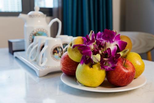 a plate of fruit with apples and flowers on a table at Aaron Hotel in Nha Trang