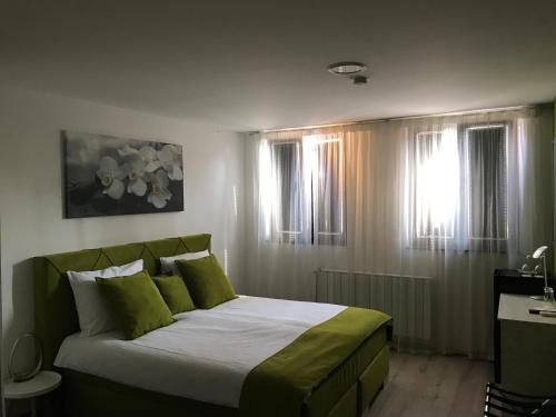 a bedroom with a large bed with green pillows at Heartland City B&B in Tuzla