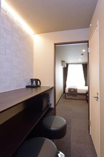 a hotel room with a desk and a bed at UU Inn Kyoto in Kyoto