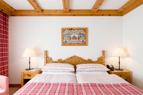 a bed in a room with two lamps and two beds at Crystal Hotel superior in St. Moritz