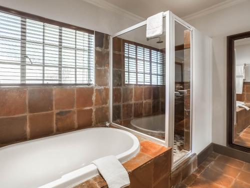 un ampio bagno con vasca e doccia di Glenburn Lodge & Spa a Muldersdrift