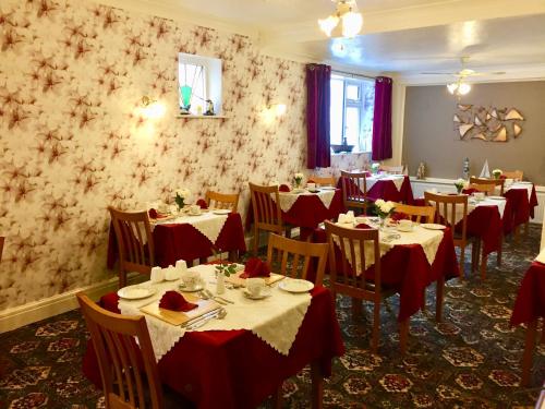 a dining room with tables and chairs with red table cloth at The Northdale Hotel Ltd in Skegness