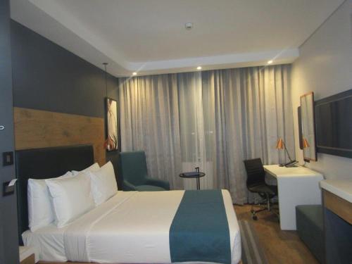 a hotel room with a bed and a desk at Garden Court Kitwe in Kitwe