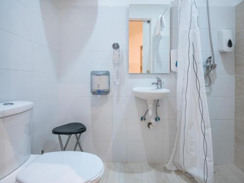 a white bathroom with a toilet and a sink at Valletta Kampnar City Living in Valletta