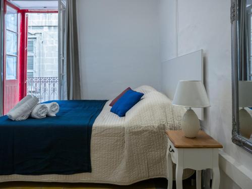a bedroom with a bed and a table with a lamp at Valletta Kampnar City Living in Valletta
