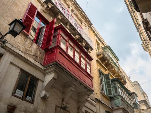 a building with red windows and a balcony at Valletta Kampnar City Living in Valletta