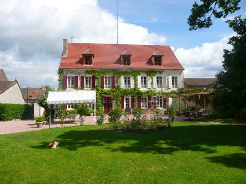 a dog laying in the grass in front of a house at Chambres d'hôtes et Roulotte Au Bonheur Du Parc in Le Breuil