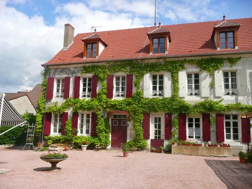a red and white house with ivy on it at Chambres d'hôtes et Roulotte Au Bonheur Du Parc in Le Breuil