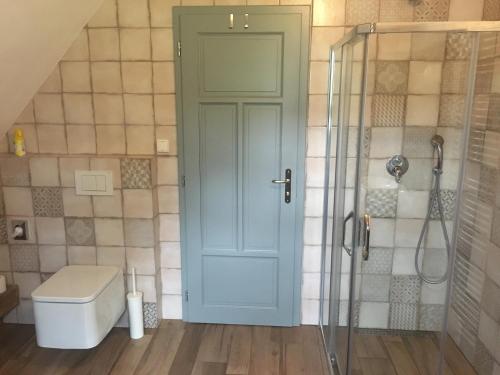 a bathroom with a toilet and a glass shower door at Chalupa u Broumovských stěn in Božanov