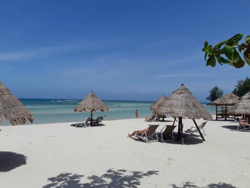a beach with chairs and straw umbrellas and the ocean at Nice Sea Resort in Srithanu