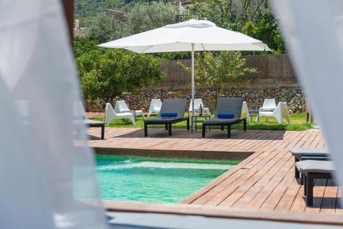 a pool with chairs and an umbrella next to a swimming pool at Hotel Turixant in Mancor del Valle