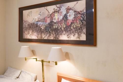 a painting on a wall above a bed with two lamps at Yoyogi House in Tokyo