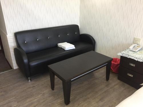 a black leather couch in a room with a table at King Lo Tung Hotel in Luodong