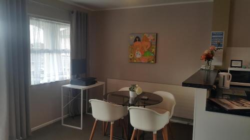 a dining room with a table and white chairs at Six On Union Motel in Rotorua