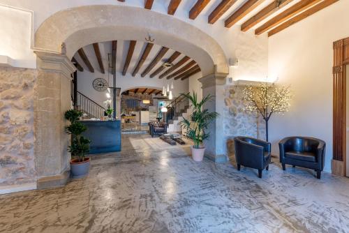 a hallway with an archway with chairs and plants at Hotel Turixant in Mancor del Valle