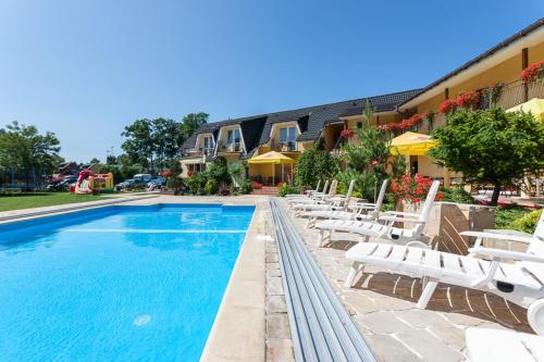a swimming pool with white lounge chairs next to a building at Perła Bałtyku in Pustkowo