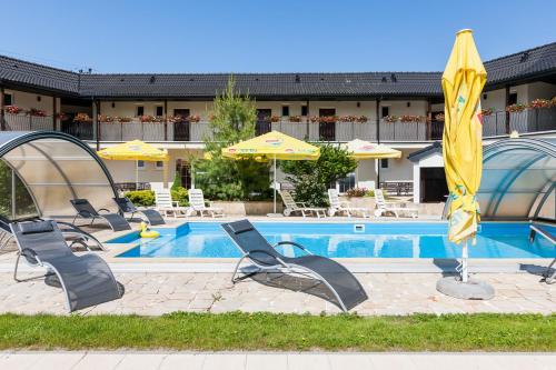 a pool with chairs and umbrellas next to a hotel at Perła Bałtyku in Pustkowo