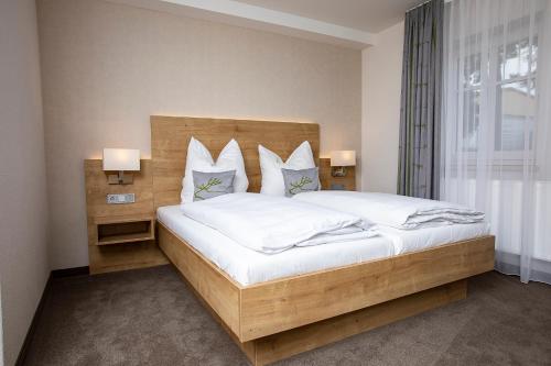 um quarto com uma cama grande com lençóis brancos e almofadas em Gästehaus - Kretschmannshof em Oberasbach