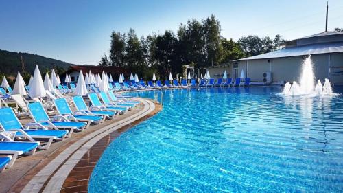 una gran piscina con sillas azules y una fuente. en Makaza Complex, en Momchilgrad